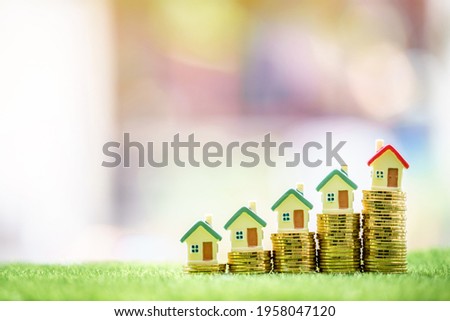 Home model put on the stack gold coin with growing interest in the public park, Savings money for buy house and loan to business investment for real estate concept.