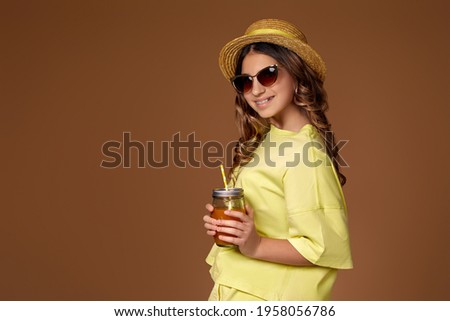 cute girl in hat with orange juice looking at camera