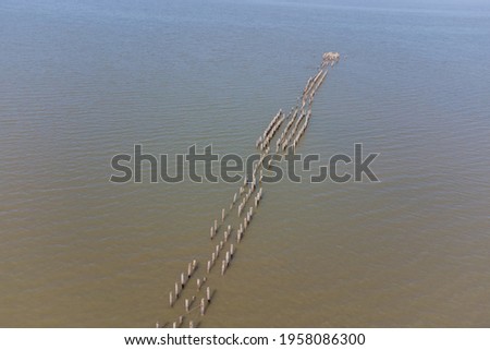 A stone spit and wooden pillars on the surface of the Kuyalnik estuary. Helicopter view