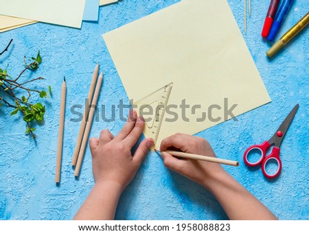 Step-by-step making of a paper weather vane by a child on a blue concrete background. Children's creativity, divas, crafts. Paper crafts Royalty-Free Stock Photo #1958088823