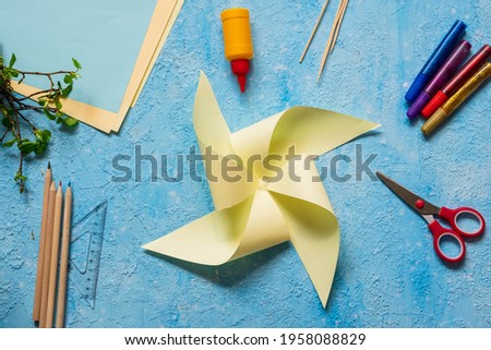 Step-by-step making of a paper weather vane by a child on a blue concrete background. Children's creativity, divas, crafts. Paper crafts Royalty-Free Stock Photo #1958088829