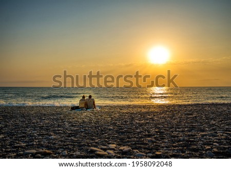 A couple of lovers meet the sunset of the sea on the shore