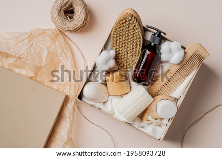 Beauty box with natural personal care cosmetics. Body brush, hair comp, amber glass shampoo bottle, moisturizer, cotton. Flat lay, top view. Royalty-Free Stock Photo #1958093728