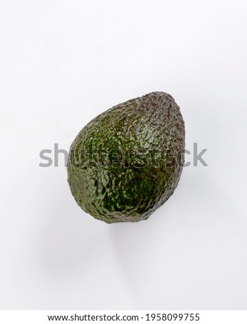 Ripe hass avocado, ready to eat. Avocado fruit covered by its rough peel, set on a well-lit white background
