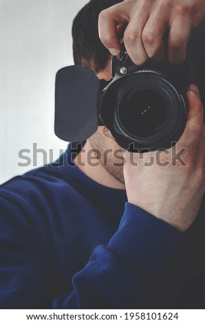 Professional photographer and in the hands of a SLR camera. The photographer is photographed through a mirror. For the photographer's business card