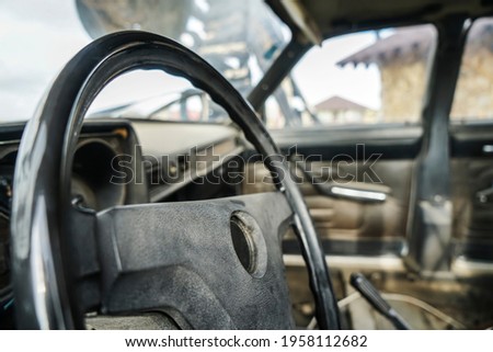 part of dusty  interior of the car with the steering wheel and doors. shallow depth of field