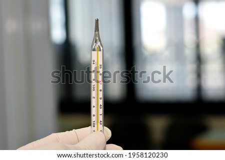 a medical personnel holding an armpit mercury temperature measuring thermometer  Royalty-Free Stock Photo #1958120230