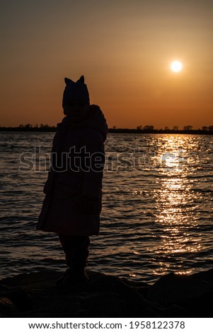 Silhouette of a small child, girls on a sunset background