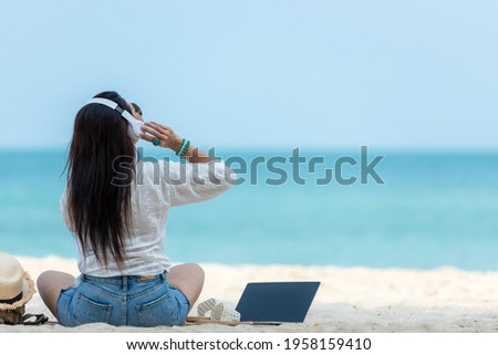 Lifestyle freelance woman listen music after using laptop working and relax on the beach.  Asia people success and together your work pastime and meeting conference on internet in holiday