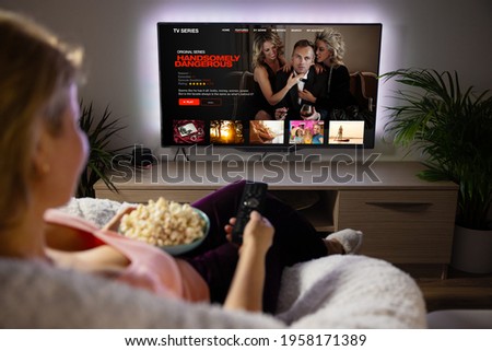 Woman watching TV series and movies via streaming service at home Royalty-Free Stock Photo #1958171389
