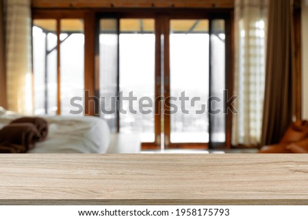 Empty wooden table with blurry background of bedroom or accommodation.