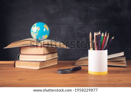 

books, globe, pencils and magnifying glass on the background of the blackboard