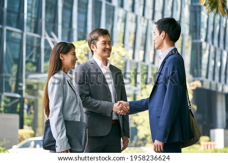 asian business associates meeting in the street in downtown financial district shaking hands Royalty-Free Stock Photo #1958236624