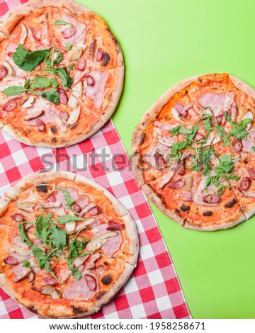 Delicious italian pizzas served on green table. Three pizza on bright green screen background, copy space web design banner. Italian concept, flat lay.