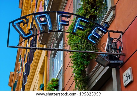 vintage neon caffe (coffee) sign hanging against colorful buildings in Rome, Italy