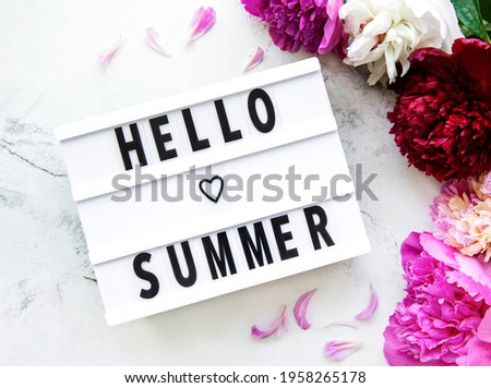 Light box with Hello Summer text and peonies flowers on a marble background