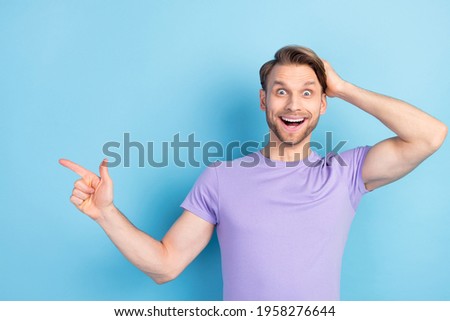 Photo portrait of surprised guy showing finger copyspace recommending isolated on pastel blue color background