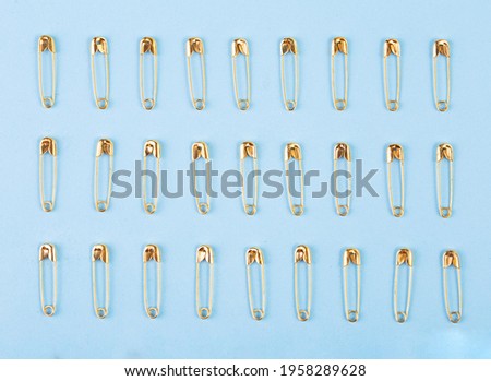 golden safety pin. pattern with gold protective needles isolated on a blue background.
