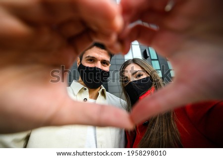 Couple wearing masks and making the sign of a heart, covid and coronavirus concept