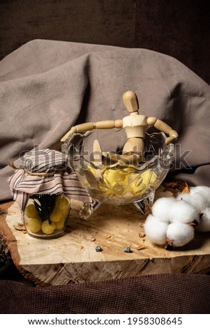 The mannequin for drawing lies in a vase with candy next to a jar with yellow sweets on a beige background. 