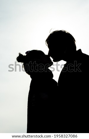 happy couple kissing silhouetted on blue sky background copy space text. Two lovers man woman embracing outdoors backlit by spring summer sun. love emotion relations