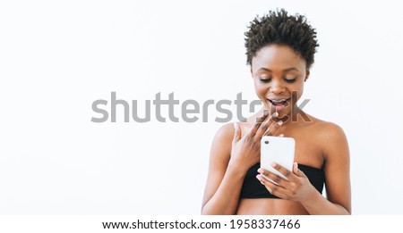 Smiling beautiful young African American woman in black top using mobile phone isolated on the white background