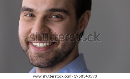 Crop close up portrait of happy millennial Caucasian man isolated on gray studio background look at camera smiling show white healthy teeth. Excited young male employee or businessman feel motivated.