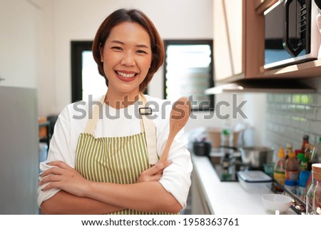 close up asian young beautiful housewife woman arm crossed and smile with happiness inside kitchen room for people lifestyle concept Royalty-Free Stock Photo #1958363761