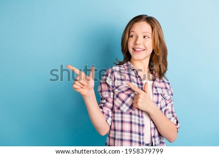 Photo of shiny cute school girl wear plaid shirt looking pointing empty space isolated blue color background