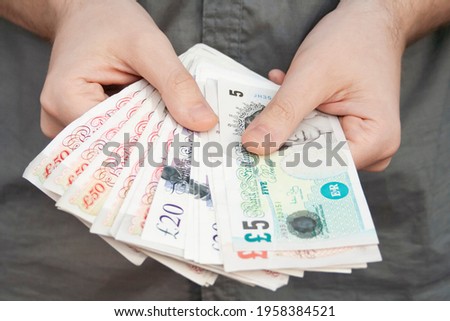 Pounds banknotes held by a man's hands Royalty-Free Stock Photo #1958384521