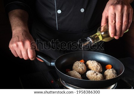 Cooking beef cutlets in a grill pan with the hands of a chef on a black background for copying the space text restaurant menu. Chef or cook adds oil