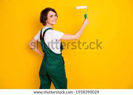 Photo of happy smiling cheerful woman painter builder painting walls restoration isolated on yellow color background