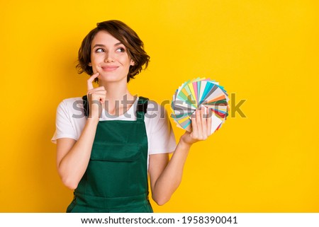 Photo of happy smiling good mood charming woman painter hold color palette dreaming isolated on yellow color background