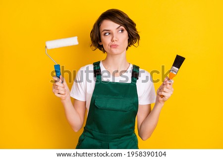 Photo of unsure nice brown hair lady hold roller brush wear uniform isolated on yellow background Royalty-Free Stock Photo #1958390104