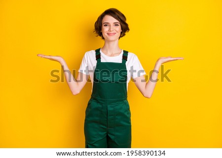 Photo of optimistic nice brown hair lady hold empty space wear uniform isolated on yellow background
