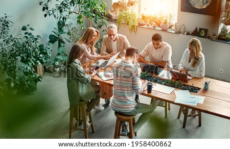 Multiracial creative people in modern office. Group of young business people and senior boss are working together with laptop, tablet, smart phone, notebook, graphs. Successful team in coworking Royalty-Free Stock Photo #1958400862