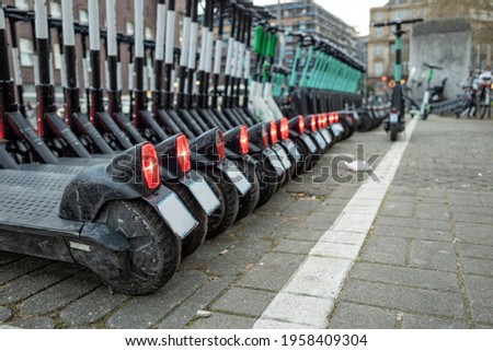 Selective focus view, row of E-scooters with Eco friendly mobility concept of sharing Electric Scooter, park on street in front of train station in Düsseldorf, Germany. Royalty-Free Stock Photo #1958409304