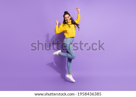 Full size photo of impressed brunette lady jump wear yellow sweater jeans sneakers isolated on purple color background