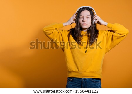 Music lovers enjoy music. A young woman in a yellow hoodie with white wireless headphones,