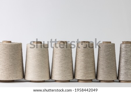 bobbins of natural fiber standing in a row, coarse linen isolated on white background. Royalty-Free Stock Photo #1958442049