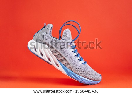 Stability and cushion running shoes. New unbranded running sneaker or trainer on orange background. Men's sport footwear. Royalty-Free Stock Photo #1958445436