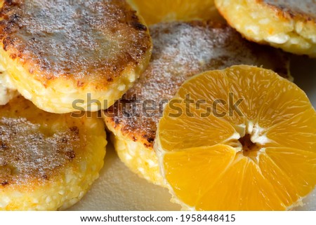 Close-up of cottage cheese pancake sprinkled with powdered sugar with orange circles. Beautiful background of a delicious, healthy breakfast