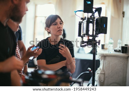 Director at work on the set. The director works with a group or with a playback while filming a movie, advertising, or a TV series. Shooting shift, equipment and group. Modern photography technique. Royalty-Free Stock Photo #1958449243