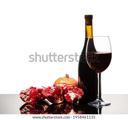 Isolated wine bottle, wine glass and juicy pomegranate on a white background
