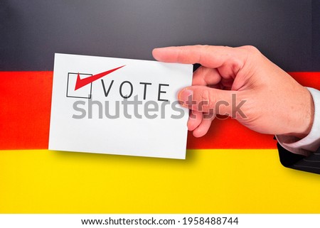 Voting in Germany. Piece of paper inscription voice. Voting at elections in Germany. Man hand with ballots in his hands. Participation in political elections in Germany. German federal elections flag