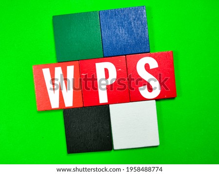 Colorful pieces of wood on green background with text WPS. Business concept.