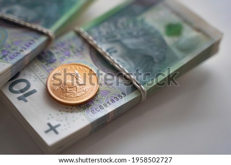 View on shiny investment coin laying on bundle of banknotes. Selective focus. Money, finance and economy background.