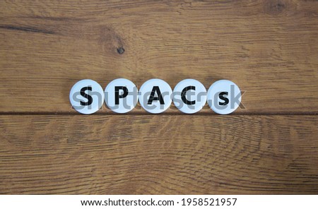 SPACs symbol. White circles with words 'SPACs, special purpose acquisition companies' on beautiful wooden background, copy space. Business and SPACs, special purpose acquisition companies concept.