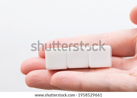 Three plain white cubes placed on  fingers