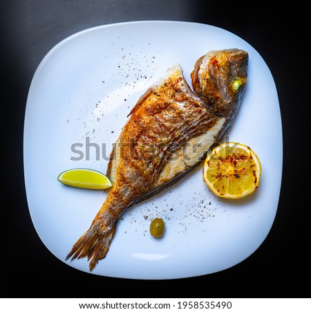 Delicious whole sea bass fish cooked on grill for dinner in seafood restaurant,shot in flat lay style on table.Download royalty free curated images collection with foods for design template